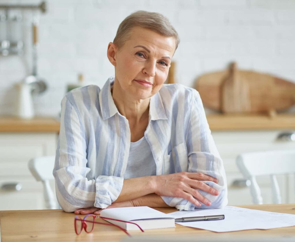 positive mature woman sitting at wooden table in k 2021 09 02 14 43 58 utc min e1764356749513